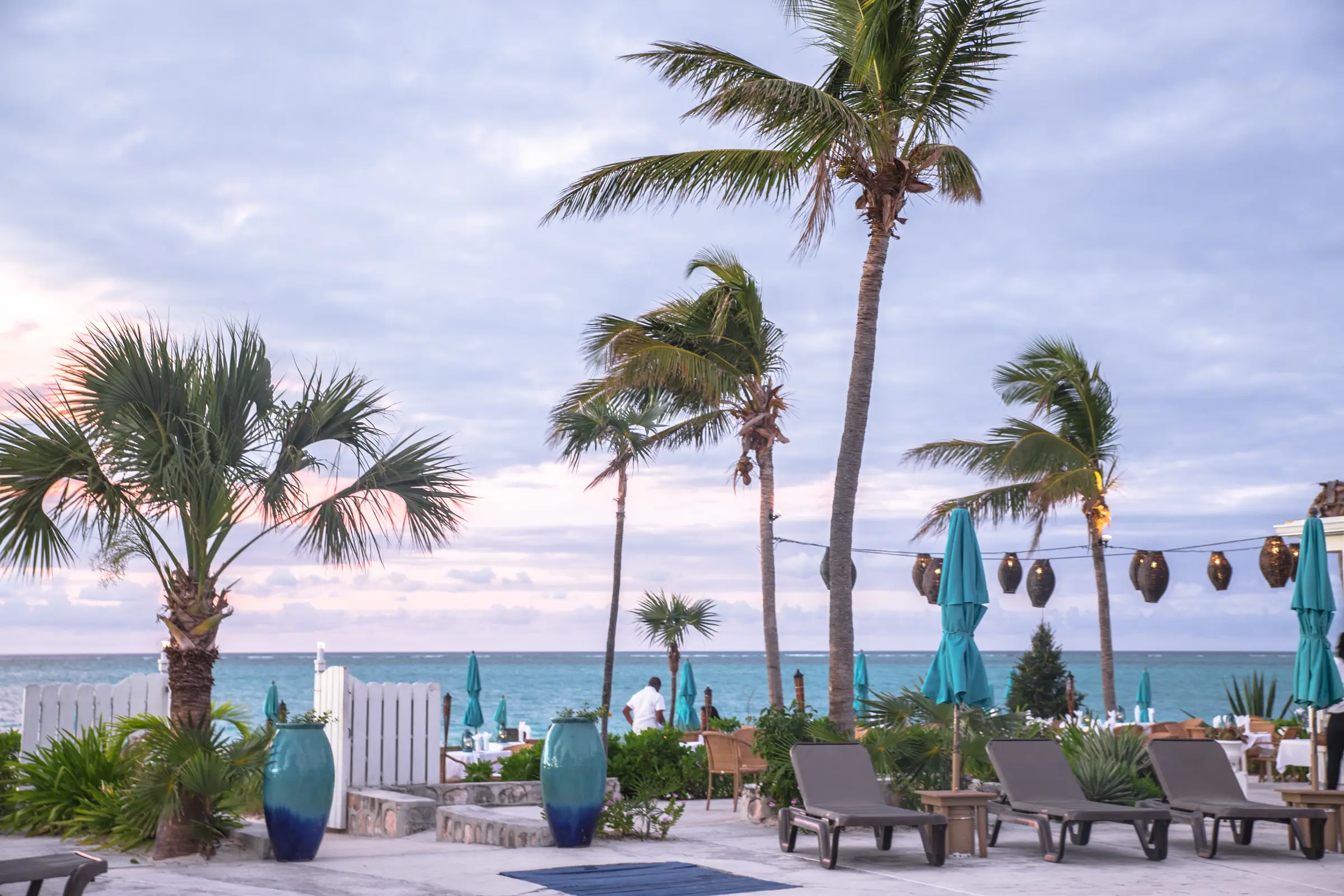 Relaxing beachfront resort terrace with palms, loungers and ocean views