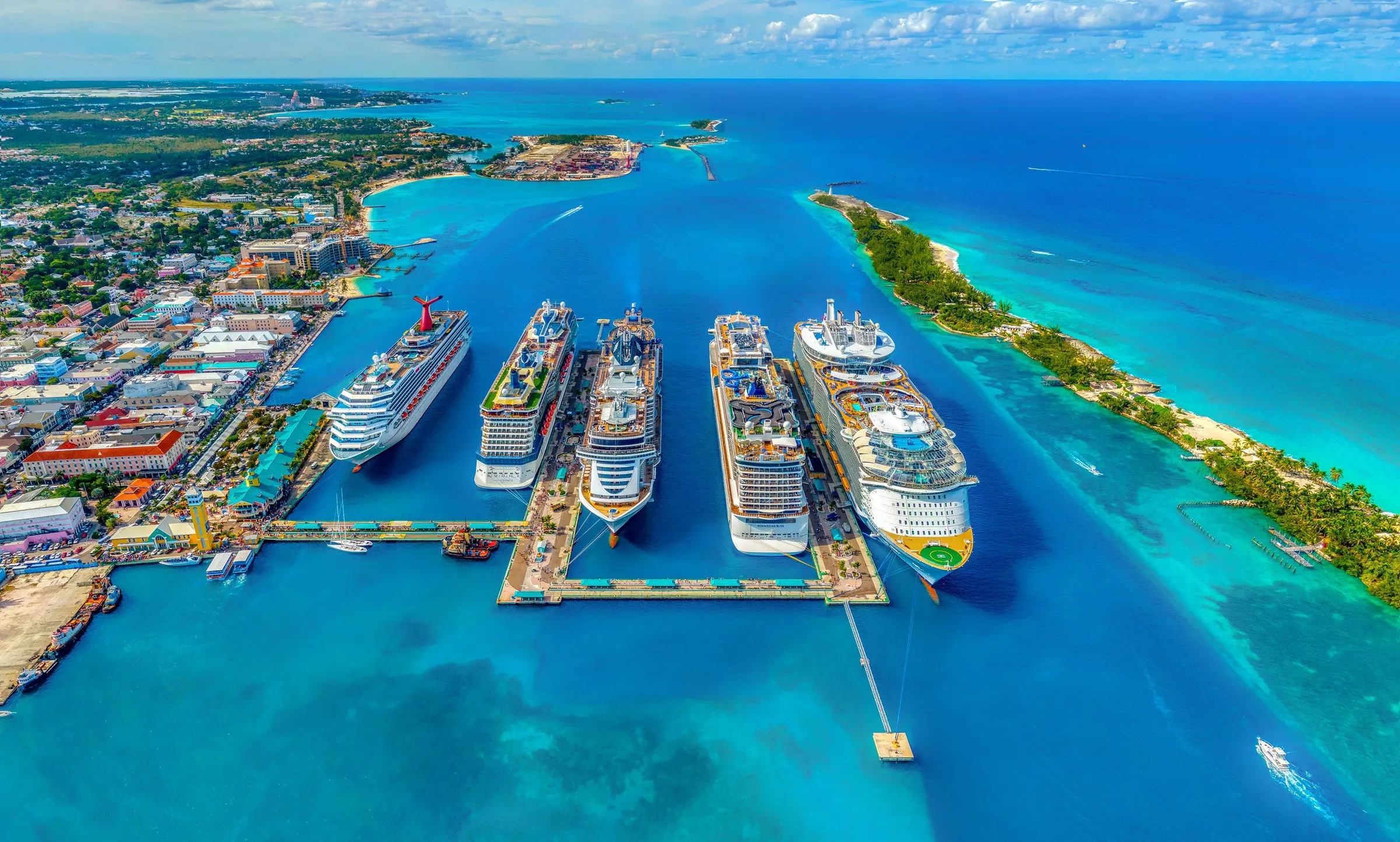 Ocean cruise ships docked in brilliant turquoise water beneath a blue sky