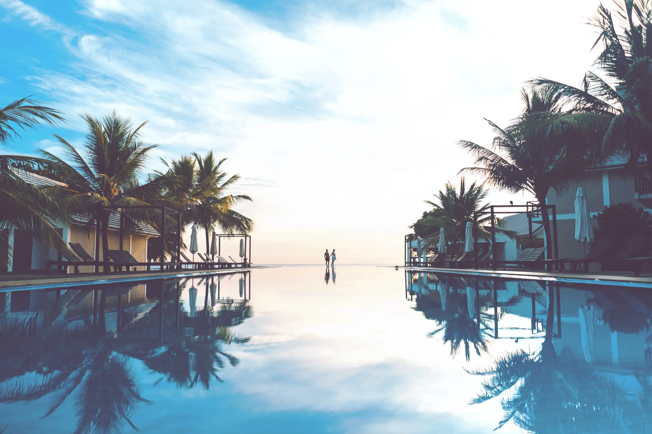 Tropical resort pool lined with palm trees